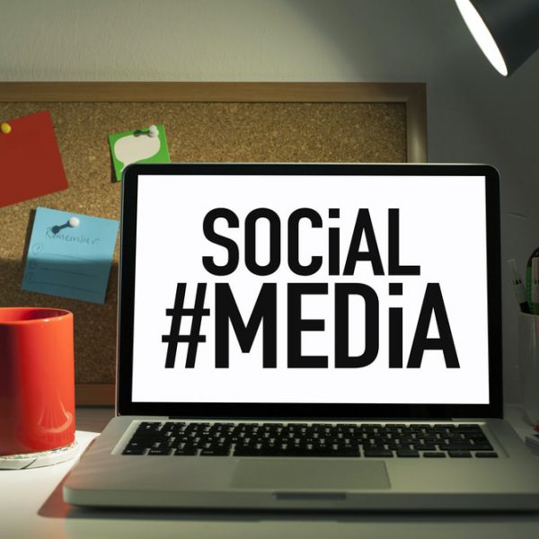 Laptop open on desk with #SocialMedia graphic on screen