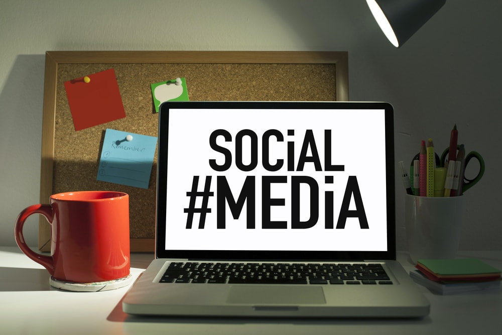 Laptop open on desk with #SocialMedia graphic on screen