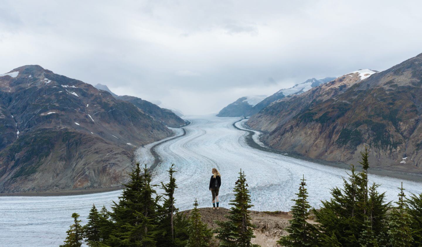 Woman hikes next to Alaskan glacier.