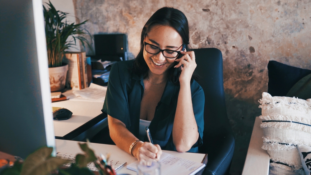 Intake staff member returning a prospective client call and taking notes, handling lead follow-up in a behavioral health practice.